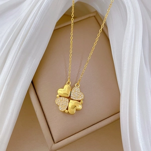Detail of gold four-leaf clover necklace with sparkling cubic zirconia on beige jewelry box