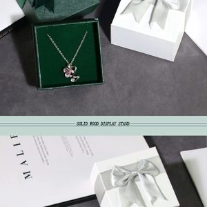 Detail of pink clover necklace inside dark green gift box with an elegant bow