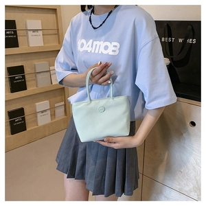 Détail d'un petit sac seau en nylon vert clair avec décoration circulaire lettre m