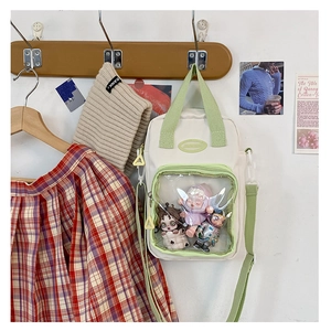Detail of a beige and light green ita bag with clear PVC window and cute charms