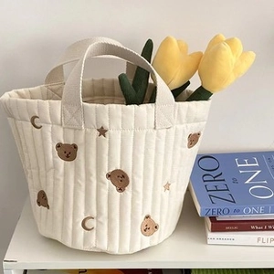 Detailed embroidery of brown bears and stars on a quilted cotton stroller bag