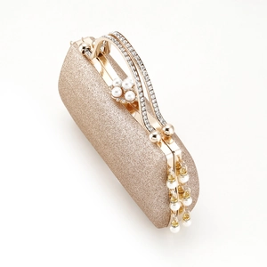 Macro shot of gold glitter evening clutch with rhinestone handle and pearl tassel detail