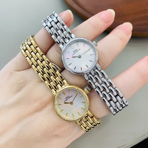 Close-up of mini gold and silver watches with pearl dial and mesh straps