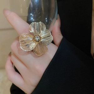 Close-up of golden hollow flower ring with crystal center on model's hand