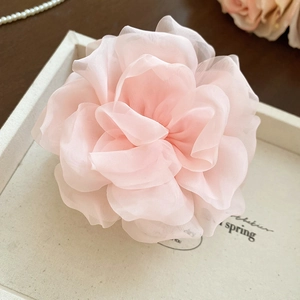 Detaillierte Makroansicht eines hellrosa geschichteten Organza Blumen Haarschmucks