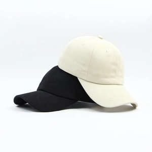 Detail of stacked cotton baseball caps in black and beige showing fine twill texture