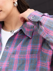 Detailed view of pink and grey flannel plaid shirt collar with grey buttons and soft fabric