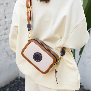 Retro crossbody camera bag in off-white with brown trim and wide fabric strap
