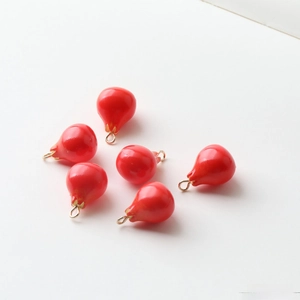 Detailed macro shot of six red resin water-drop pendants with gold metal hanging loops