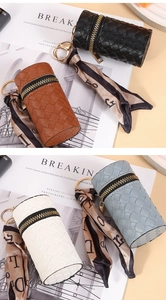 Detail of woven mini cylinder purses in four colors with decorative ribbon and gold clasp