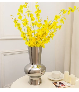 Silver mirror ceramic vase with yellow orchid flowers in a cozy home decor setting