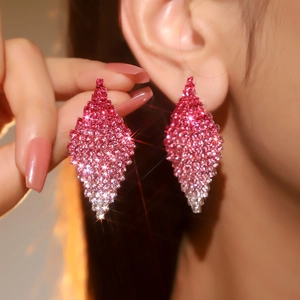 Close-up of diamond rhombus drop earrings with red to pink gradient pavé gems