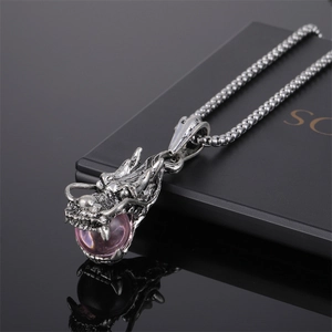 Détail du pendentif tête de dragon en argent avec perle rose sur fond noir réfléchissant