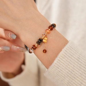 Gros plan d'un bracelet en œil de tigre avec breloque dorée sur pull en maille
