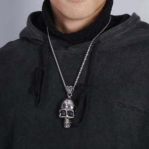 Close-up of a silver skull pendant on a rope chain worn with a black hoodie