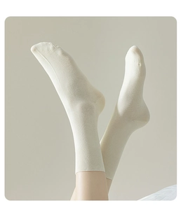 Close-up detail of women's beige cotton crew socks with ribbed cuffs and soft breathable fabric.