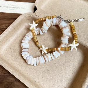 Close-up of geometric shell beaded bracelet set with star pendant on a natural tray