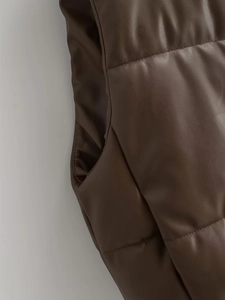 Close-up of deep brown faux leather vest showing pocket details and stitching texture