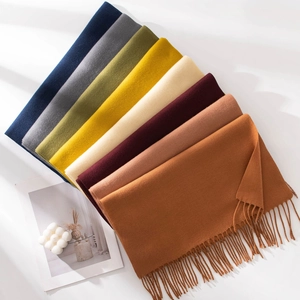 Posa piatta di sciarpe colorate effetto cashmere con frange in varie tonalità neutre