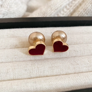Close-up of red flocked heart studs with gold beads on soft beige knit fabric