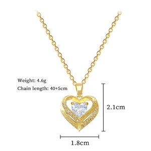 Macro detail of gold double-layered heart necklace with crystal inlay and engraved frame