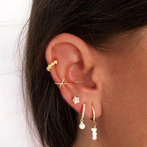 Close-up of gold plated layered earrings set with pearls and rhinestones on ear