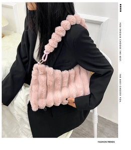 Close-up of pink plush handbag with unique pom-pom shoulder strap and pleated texture detail