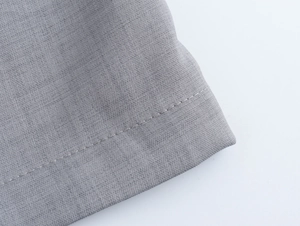 Gros plan détaillé sur la texture du tissu sergé gris et les coutures du pantalon de costume