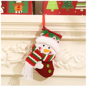 Detail of knitted snowman Christmas stocking hanging on a white fireplace with festive gift boxes