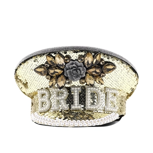 Detailed view of the gold sequined military hat with pearl BRIDE text and rhinestones