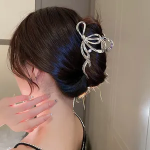 Detail view of silver metal bow hair claw with elegant pearl embellishment on a hairstyle
