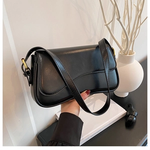 Detail of black faux leather crescent shoulder bag with elegant gold adjustable buckle