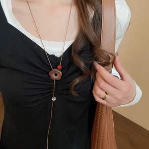 Gros plan d'un pendentif fleur en bois vintage avec perle rouge sur robe noire