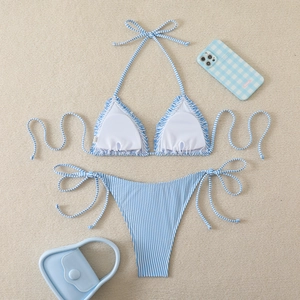Detailed flat lay of blue and white striped bikini with ruffled edges on beige carpet