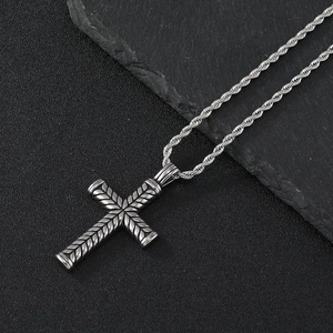 Macro shot of a silver textured cross pendant on a stainless steel twist chain