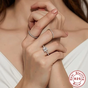 Close-up of three 925 sterling silver rings including square-cut solitaire and band sets