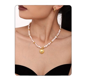Close-up of elegant freshwater pearl necklace with gold pendant and matching earrings