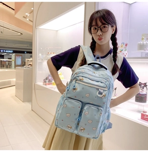 Detail of light blue school backpack with cute bear print and double front pockets