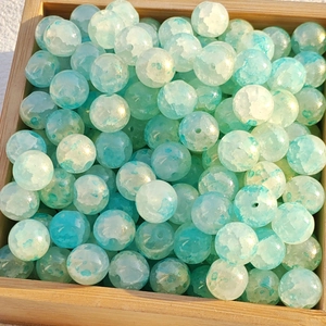 Macro view of blue and white watercolor glass beads in a light wooden tray