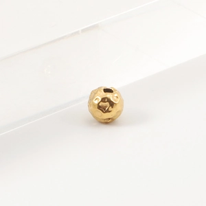 Macro shot of a gold hammered stainless steel bead showing detailed metallic texture