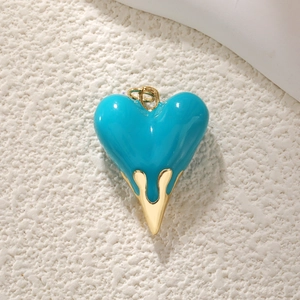Detailed view of heart-shaped pendant with teal enamel and gold dripping metal effect