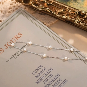 Detail of freshwater pearl necklace laid on a vintage French notebook with soft lighting