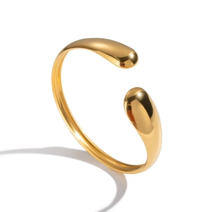 Detail shot of minimalist gold open bangle with polished teardrop ends and glossy finish