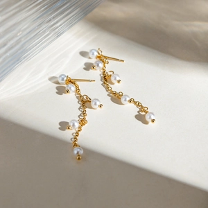 Detail view of 18K gold stainless steel earrings with white grape-shaped pearls