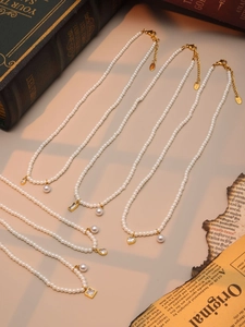Detailed flat lay of stainless steel pearl necklaces with zircon heart and shell pendants