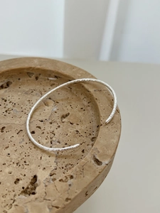 Gros plan sur un bracelet jonc minimaliste en argent 925 avec texture de papier d'aluminium