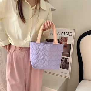 Close-up of a lilac quilted heart-patterned handbag with contrasting soft padded handles