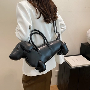 Unique black dachshund-shaped leather handbag with shoulder strap worn by a model