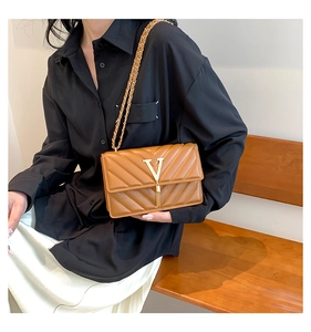 Detailansicht der braunen gesteppten Ledertasche mit goldenem V-Logo und Quasten-Kettenriemen