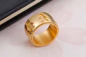 Macro view of gold-plated chain spinner ring with hollow child silhouettes engraving